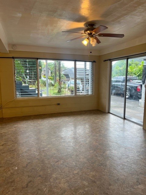 A room with a ceiling fan and sliding glass doors.